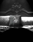 Cat Peekaboo pillow by Muahaha!  Black and white photo of the 16x16 faux suede pillow showing a cat wearing a witch hat's face resting on an antique bed in a victorian mansion.  The perfect gothic, horror gift!